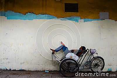 Tired Asian cyclo driver taking a nap on his cyclo with copy space for text or advertising on colorful background Editorial Stock Photo