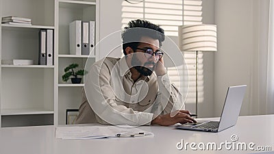 Tired bored Arabian Indian man businessman lazy employee manager boring job working with laptop studying write business Stock Photo