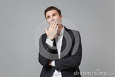 Tired boring young business man in classic black suit shirt posing isolated on grey wall background. Achievement career Stock Photo