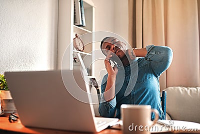 Tired business man with neck pain on a laptop and phone call, looking stressed and stretching bad, strained muscle or Stock Photo