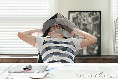 Tired business man sleeping atc his desk overing his head with a laptopin his office Stock Photo