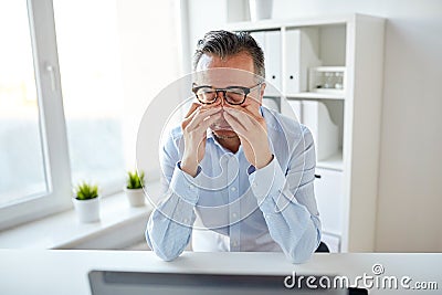 Tired businessman in glasses with laptop at office Stock Photo