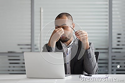 Exhausted male employee massage eyes suffering from headache Stock Photo