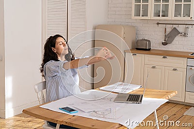 Tired businesswoman stretch work remotely on laptop on project blueprint at home office in covid-19 Stock Photo