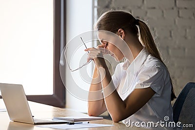 Tired businesswoman taking off glasses, suffering from eye strain Stock Photo