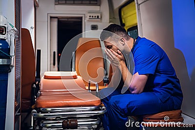 Tired corpsman in medical uniform sits inside the ambulance Stock Photo