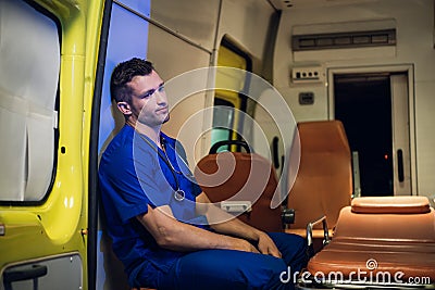 Tired corpsman in uniform sits inside the ambulance car Stock Photo