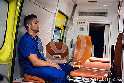 Tired corpsman sitting inside the ambulance car, meditating Stock Photo
