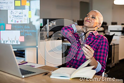 Tired creative businesswoman sitting on desk Stock Photo