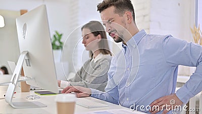 Tired Creative Man having Back Pain in Modern Office Stock Photo