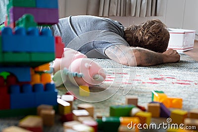 Tired dad taking a nap in a messy home. Parenthood Stock Photo