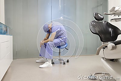 Tired dentist sitting on dental saddle - price of success Stock Photo