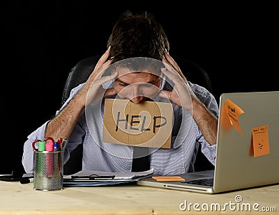 Tired desperate businessman in stress working at office computer desk holding sign asking for help Stock Photo