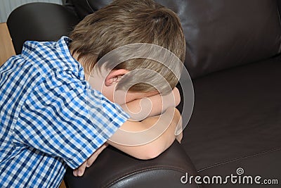 Tired or distressed little boy, face down on sofa Stock Photo