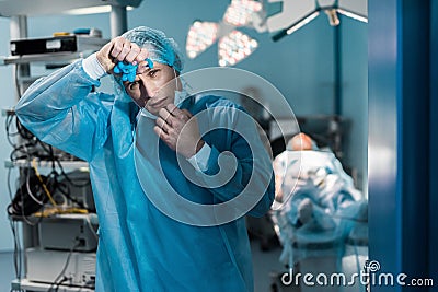 tired doctor removing medical mask and touching forehead Stock Photo