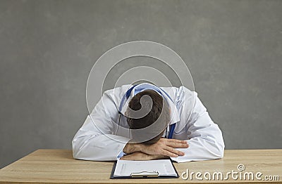 Tired and exhausted male doctor sleeps sitting at a table after a hard day's work. Stock Photo