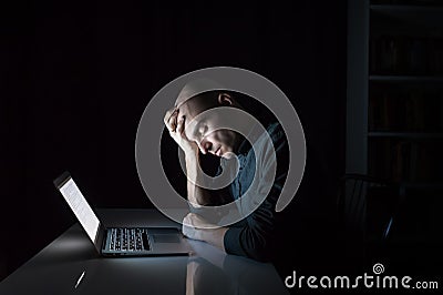 Tired or exhausted man at computer late in the evening Stock Photo