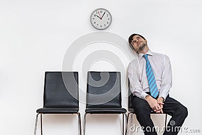 Tired and exhausted man is sitting in waiting room on chair. Stock Photo