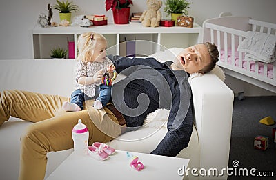 Tired father sleeping with baby on his lap Stock Photo