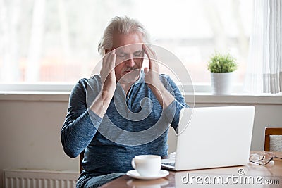 Tired senior man touching temples feeling headache working on la Stock Photo