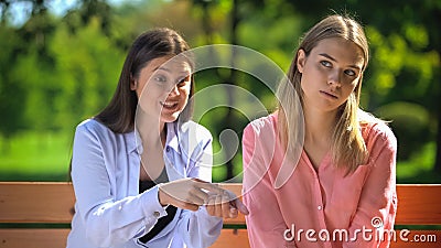 Tired female listening to annoying friend sitting outdoors, envy, selfishness Stock Photo