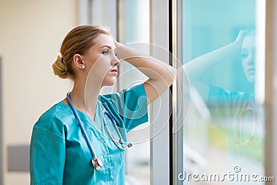 Tired female nurse in hospital corridor Stock Photo