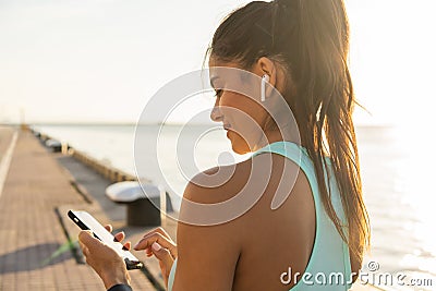 Tired fitness woman sweating taking a break listening to music on phone after difficult training. Stock Photo