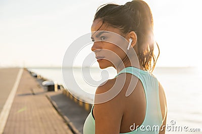 Tired fitness woman sweating taking a break listening to music on phone after difficult training. Stock Photo