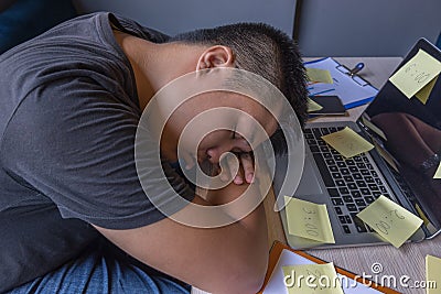 Young freelancer fall asleep on laptop at unorganized workplace Stock Photo