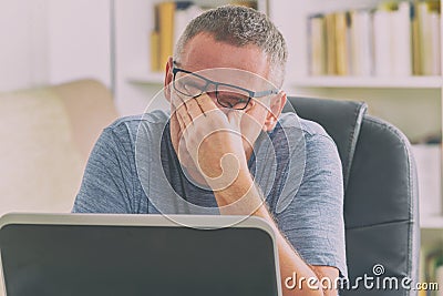 Tired freelancer man rubbing his eyes Stock Photo
