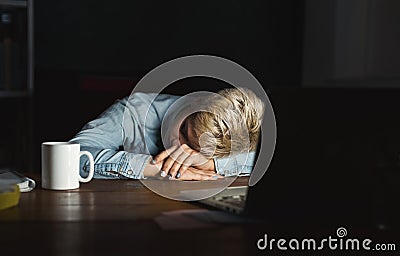 Tired freelancer working on laptop at home until late evening Stock Photo