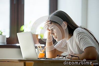 Tired frustrated woman attentively reading a contract on laptop Stock Photo