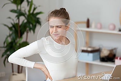 Tired girl feeling back pain rubbing muscles after sedentary work Stock Photo