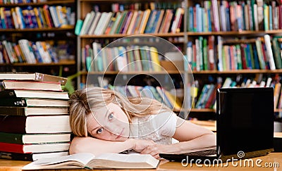 Tired girl in the library teaches before exams Stock Photo