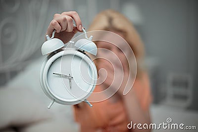 Tired girl wants to sleep and sets the alarm. Stock Photo