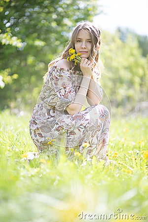 Tired but happy girl sitting on the lawn of the Park with a bouquet of flowers Stock Photo