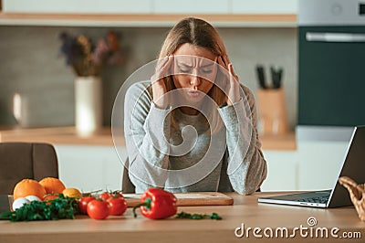Tired, having headache. Beautiful young woman is on the kitchen Stock Photo