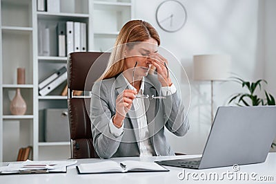 Tired, having headache. Woman in business formal clothes is working in office Stock Photo
