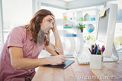 Tired hipster working on graphics tablet and computer Stock Photo