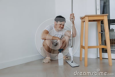 Tired househusband man sit on the floor after mopping the room. Stock Photo