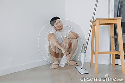 Tired househusband man sit on the floor after mopping the room. Stock Photo