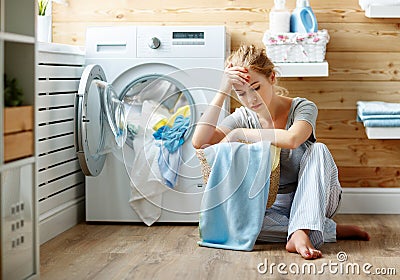 Tired housewife woman in stress sleeps in laundry room with washing machine Stock Photo