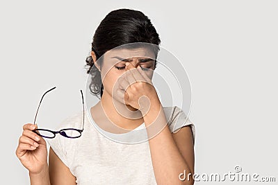 Tired Indian girl taking off glasses, feeling eye strain Stock Photo