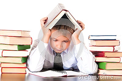 A tired, lagging schoolboy boy sits in a library with books and learns lessons. Unwillingness to learn Stock Photo