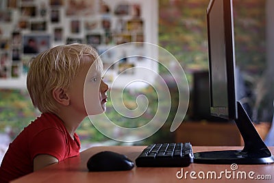 Tired little blond boy sits his nose buried in a monitor PC. Internet and preschooler Stock Photo