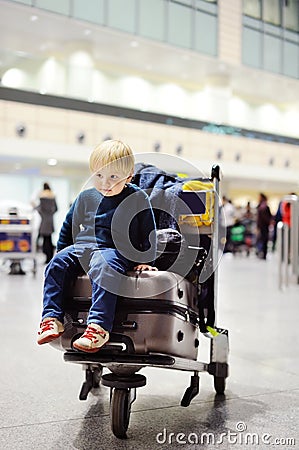 Tired little boy sitting on suitcases on international airport Stock Photo