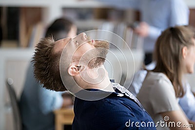 Tired male employee falling asleep in chair at workplace Stock Photo