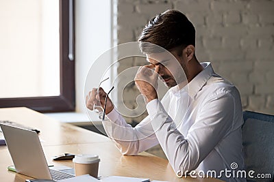 Millennial office worker taking off eyeglasses suffers from eyes strain Stock Photo