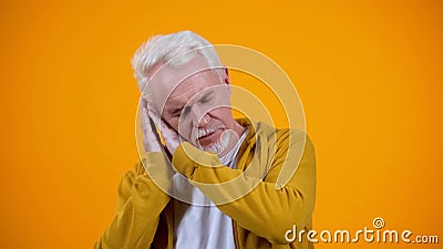 Tired male pensioner demonstrating sleep gesture, bright background, relaxation Stock Photo