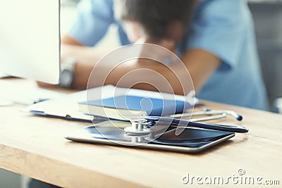 Tired man doctor sleeps lying on his hands while sitting at a computer desk. Doctor works on a computer in the clinic Stock Photo